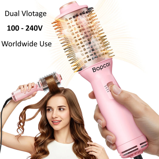 Pink  dual-voltage round hair styling brush with 100–240V worldwide compatibility, shown in hand with a woman styling her hair in the background.